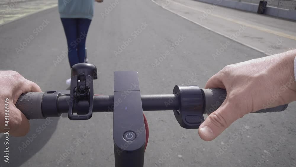 First-person view. A man follows a woman on his electric scooter. First-person view. A man follows a woman on his electric scooter.