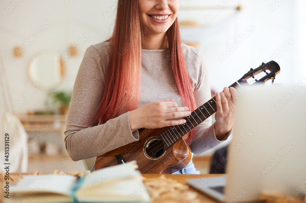 Fototapeta premium Faceless young woman playing ukulele. Online music tuition.