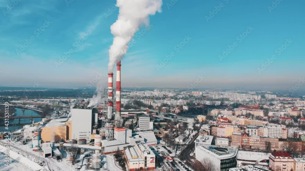 Industrial area of Wroclaw, Poland. Smoke coming out from the chimneys of the CHP plant polluting the blue sky. Aerial view of the buildings in the city. Clear blue sky in the background. Industrial area of Wroclaw, Poland. Smoke coming out from the chimneys of the CHP plant polluting the blue sky. Aerial view of the buildings in the city. Clear blue sky in the background.