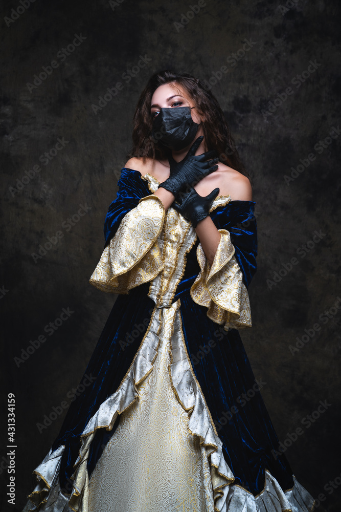 Beautiful woman in renaissance dress, face mask and gloves on abstract dark background, coronavirus, covid-19 protection concept