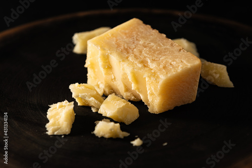 sliced parmesan cheese with chipped pieces, on a dark background