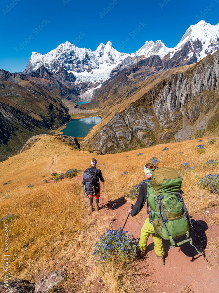 Girl backpackers hiking towards amazing Jahuacocha lakes at Huayhuash circuit, Cordillera Huayhuash, Peru, South America