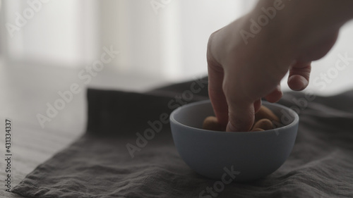 Fotografie Man pour chocolate dragee in blue bowl on linen cloth