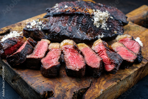 Traditional barbecue dry aged wagyu Brazilian picanha steaks from the sirloin cap of rump beef sliced and served as close-up on a rustic wooden board photo