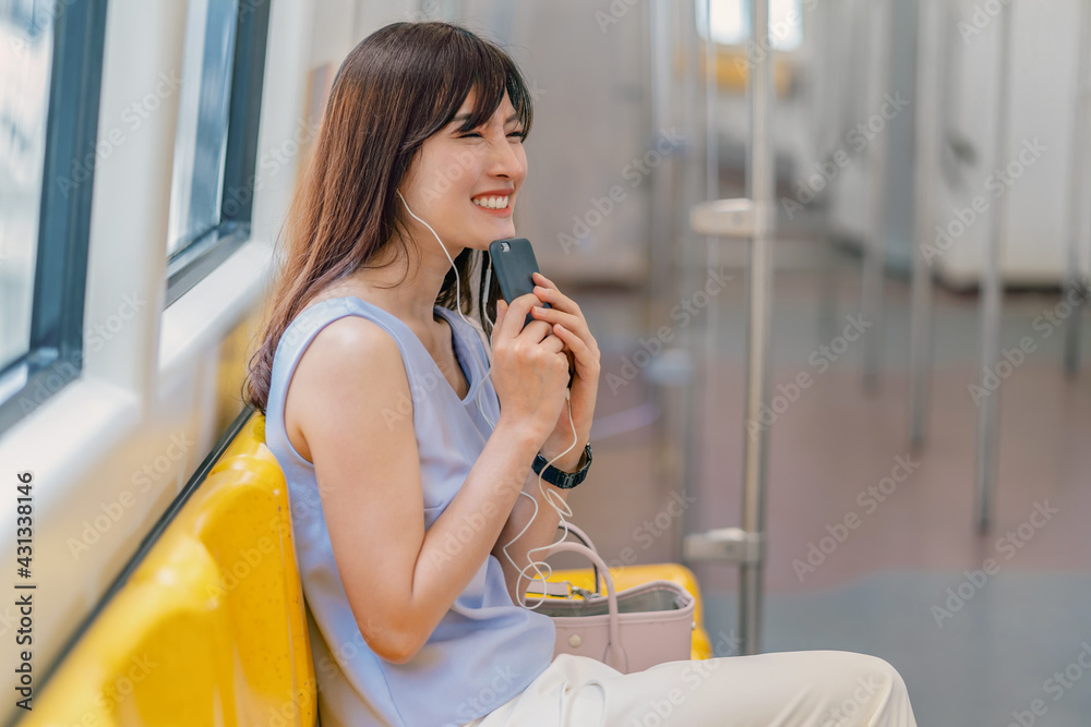 Young Asian woman passenger listening music via smart mobile phone in subway train when traveling in big city,japanese,chinese,Korean lifestyle and daily life, commuter and transportation concept