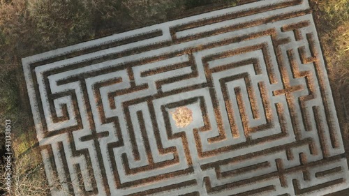 Geometrical background, top down view of a symmetrical labirynth. Aerial shot of a green maze, path and challenge concept.