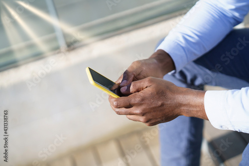 Hands of unrecognizable black man using a smartphone.