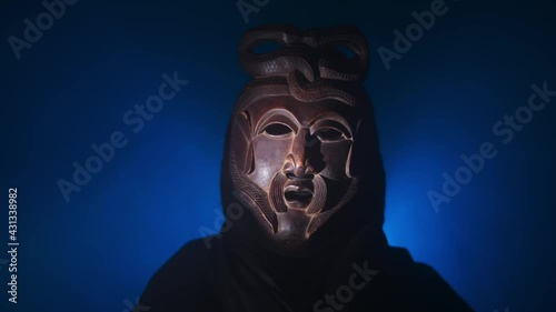 Creepy, masked cultist standing in a dark room. Scary horror scene, mysterious man in a tribal mask isolated on a black background. Eerie mask, devil concept.