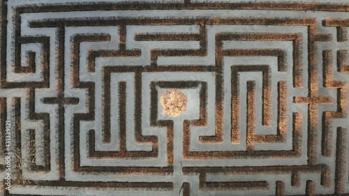 Geometrical background, top down view of a symmetrical labirynth. Aerial shot of a green maze, path and challenge concept.