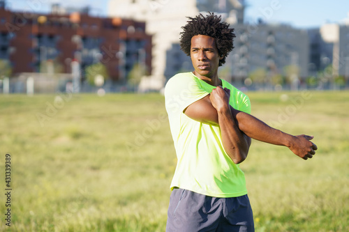 Black man with afro hair doing stretching after running outdoors.