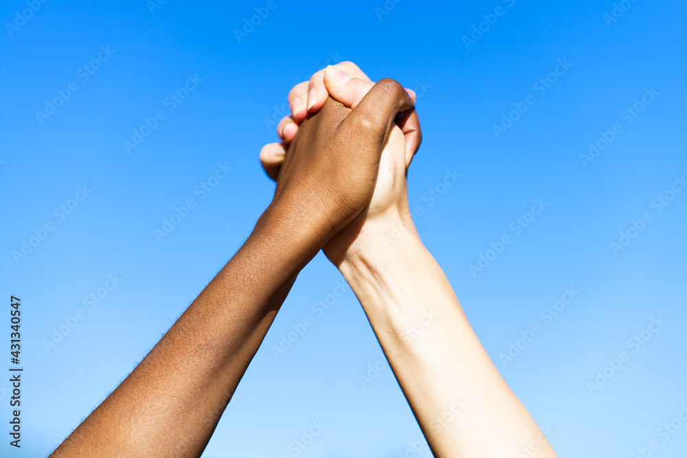 Multiethnic women's hands together against blue sky. Multiethnic women's hands together against blue sky.