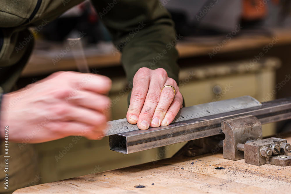 Mechanic measuring metal bar before sawing it Mechanic measuring metal bar before sawing it