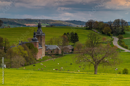 13th century castle in the rolling hill landscape and green meadows in Belgium with winding roads and a dramatic sky. photo