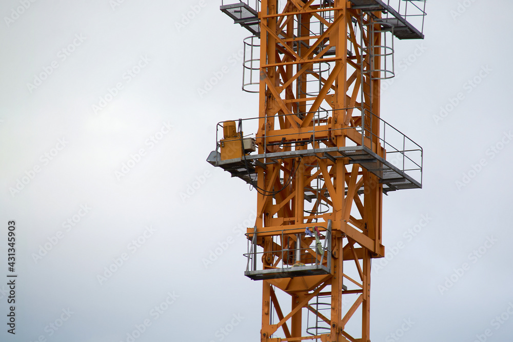 yellow construction crane close-up.construction of houses.against a cloudy sky yellow construction crane close-up.construction of houses.against a cloudy sky
