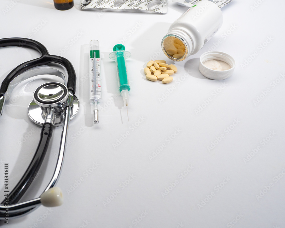 syringe, stethoscope and a jar of pills on a white background