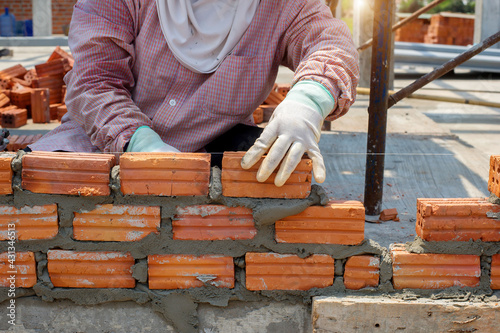 masonry worker make concrete wall by cement block and plaster at construction site