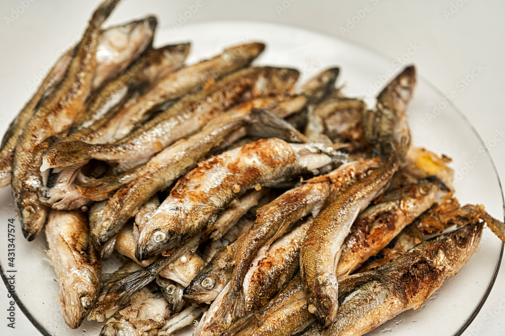 Fried golden small smelt delicious fish on a white plate Fried golden small smelt delicious fish on a white plate