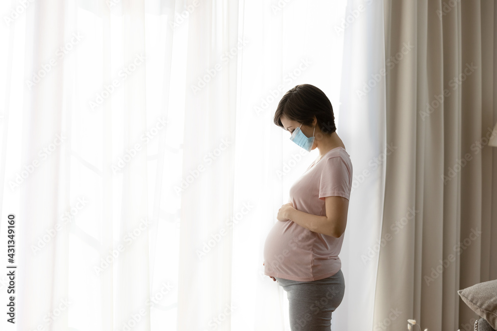 Young Caucasian pregnant woman wear facemask worried about giving birth during corona virus covid-19. Millennial female in facial mask anxious about pregnancy in coronavirus lockdown pandemics. Young Caucasian pregnant woman wear facemask worried about giving birth during corona virus covid-19. Millennial female in facial mask anxious about pregnancy in coronavirus lockdown pandemics.