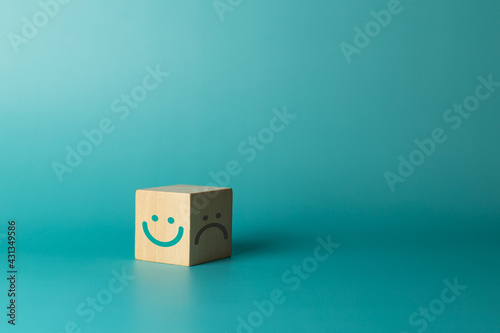 Wooden cube with smiley face and bad face on green background. Service rating, satisfaction concept