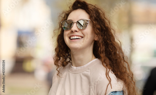 Beautiful smiling young caucasian girl with curly hair outdoors