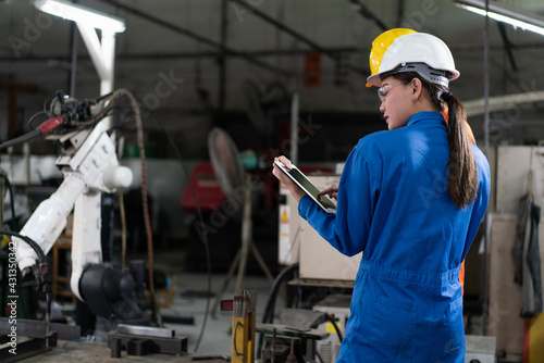 Wallpaper Mural Female automation engineers wear a blue uniform with helmet safety inspection control a robot arm welding machine with a tablet in an industrial factory. Artificial intelligence concept. Torontodigital.ca