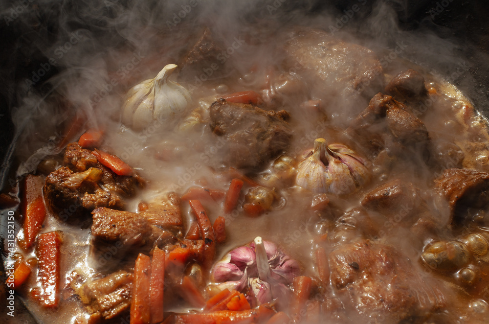Meat with garlic and carrots cooked in a large cauldron Meat with garlic and carrots cooked in a large cauldron