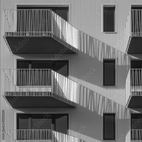 Detail of an apartment building with balconies on a sunny day. Distinctive lines, light and shadow.
