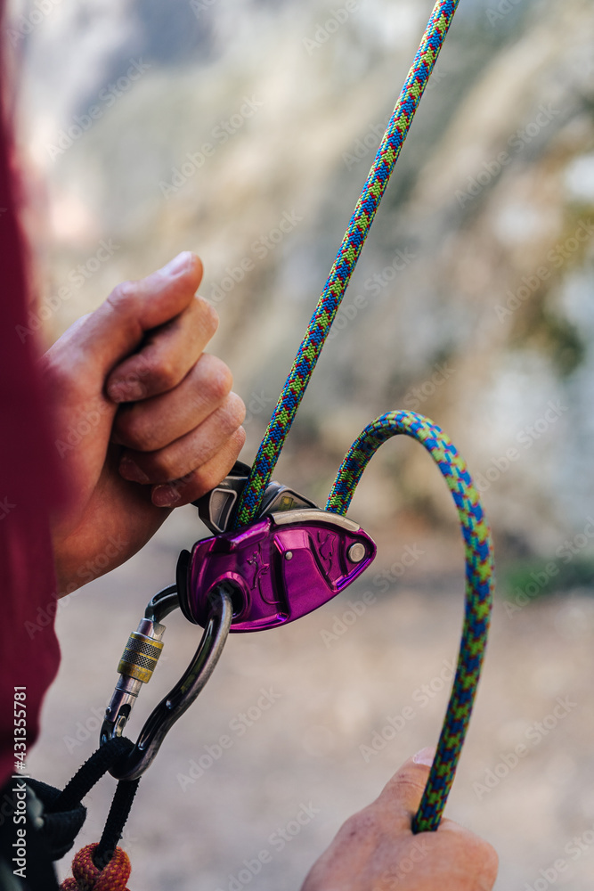 Close up photo of a belay device used by climbers. Climbing gear in action.  Belay with a rope and a technical climbing equipment. Stock Photo | Adobe  Stock