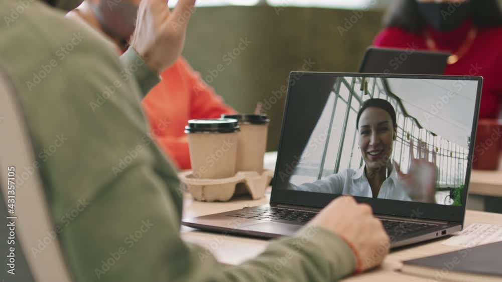 Mid-section shot with PAN of unrecognizable businessman sitting at desk and talking to female colleague on video call via laptop Mid-section shot with PAN of unrecognizable businessman sitting at desk and talking to female colleague on video call via laptop