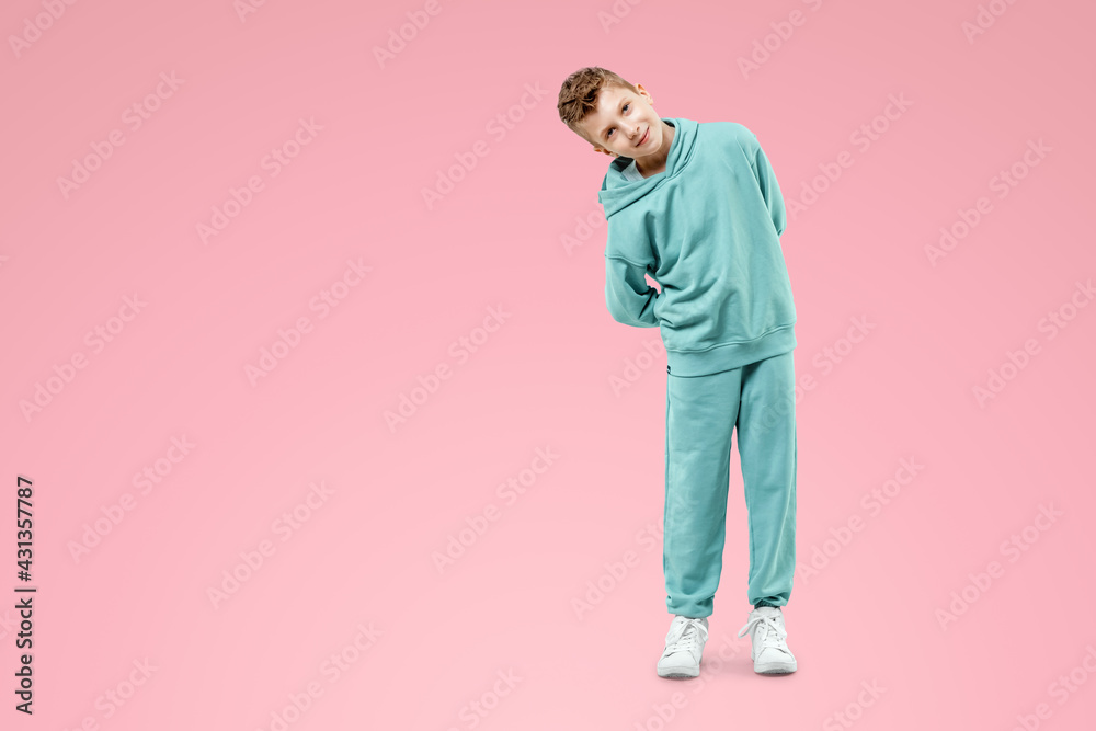 Fototapeta premium Portrait, cute stylish boy in a blue suit on a pink background. Studio portrait of a child, modern design, trendy background, turquoise. Copy space.