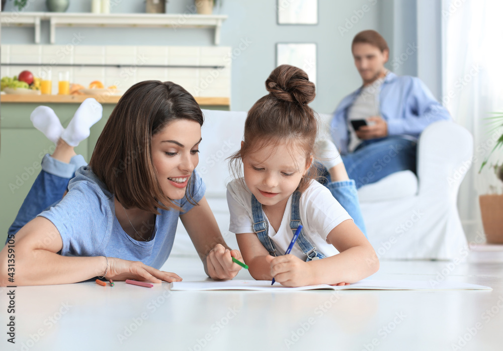 Happy mother smilling daughter lying on warm floor enjoying creative activity, drawing pencils in albums. Happy mother smilling daughter lying on warm floor enjoying creative activity, drawing pencils in albums.