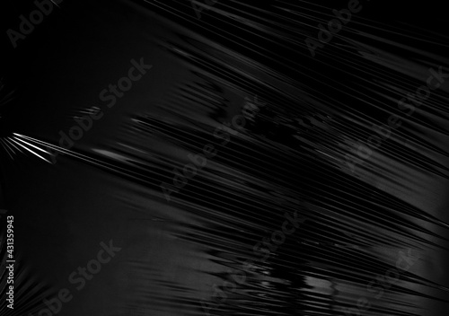 a transparent stretch plastic wrap on black background. realistic plastic wrap texture for overlay and effect. wrinkled plastic pattern for creative and decorative design.