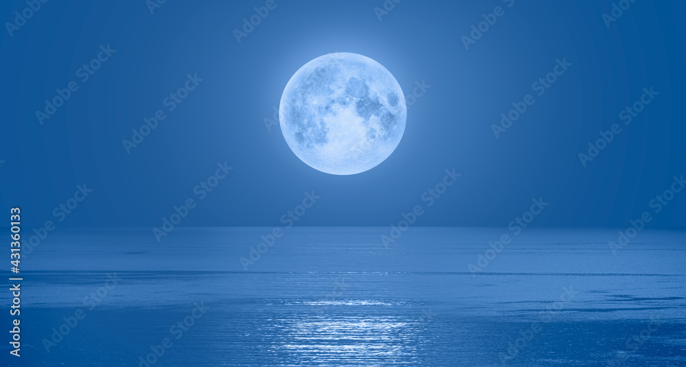 Full moon rising over empty ocean at night 