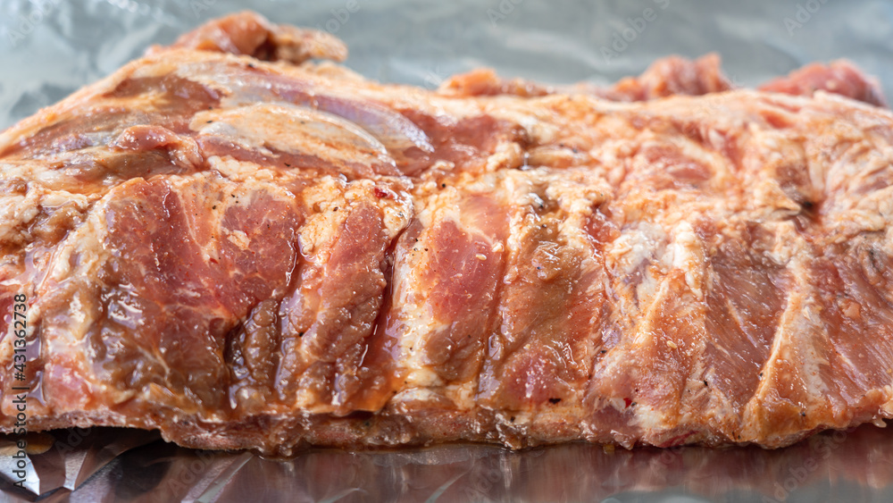 A raw large piece of Pork rib or Spare rib which is already marinated with spicy pepper power and BBQ ingredient. Food preparation, close-up and selective photo.
