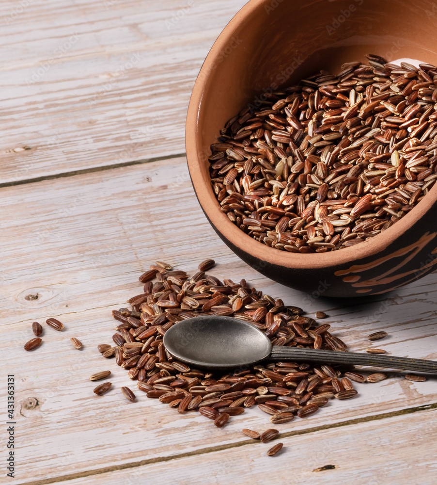brown rice in ceramic bowl with metal spoon on wooden background brown rice in ceramic bowl with metal spoon on wooden background