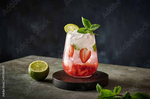 Homemade fresh iced lemonade with strawberries , lime and mint on a wooden background. Summer healthy drink 