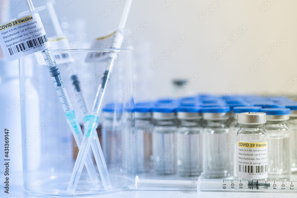 Glass bottle vial and syringe with Covid-19 Coronavirus vaccine in a research medical facility lab. Ampoules with cure on the medical worker laboratory table. Sars-cov-2 pandemic concept. Glass bottle vial and syringe with Covid-19 Coronavirus vaccine in a research medical facility lab. Ampoules with cure on the medical worker laboratory table. Sars-cov-2 pandemic concept.
