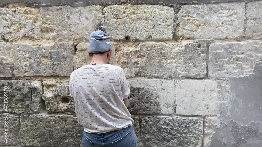 Jeune femme ponçant un mur en pierre bordelaise
