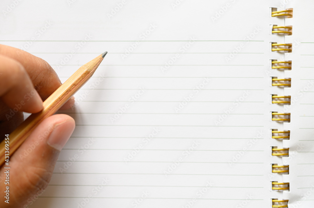 Man hand using a pencil writing ,drawing on a white book,letter