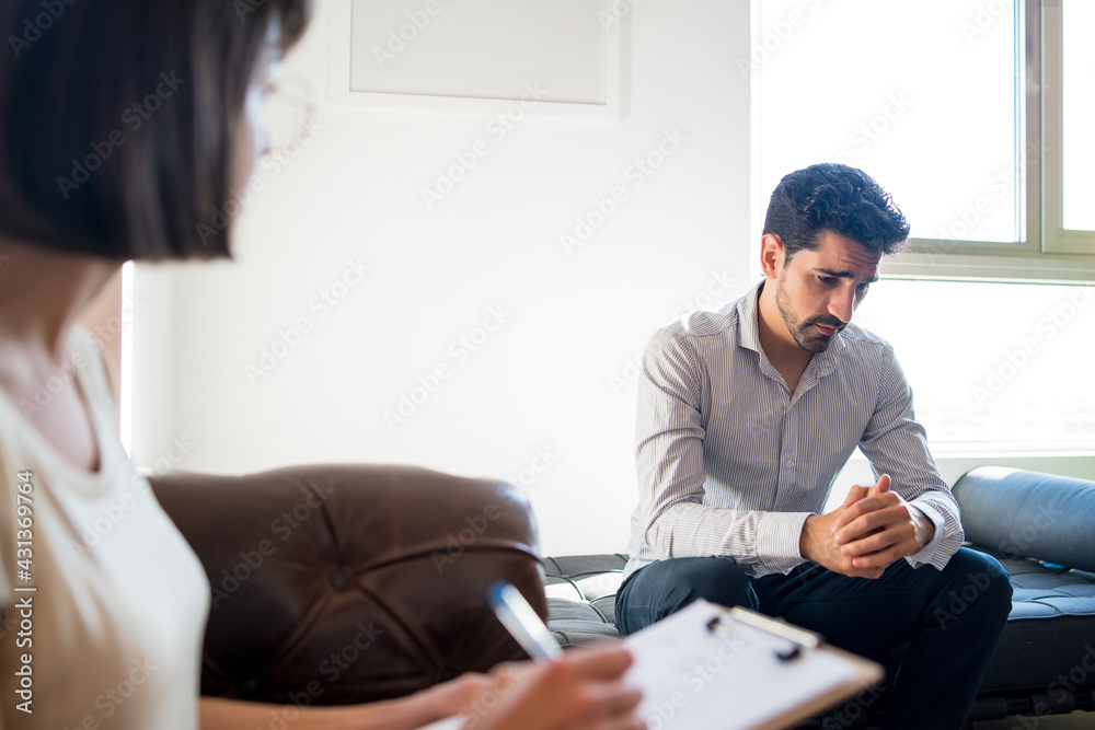 Psychologist taking notes during therapy session. Psychologist taking notes during therapy session.