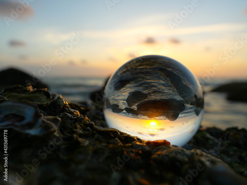 Lens optic ball view of ocean coastline and setting sun. 