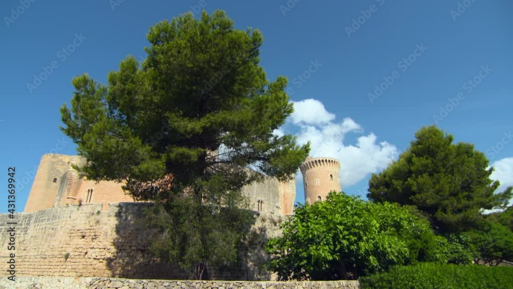 Lockdown Of The Castell De Bellver Fortification On A Bright Sunny Day, With Clear Blue Skies, Lush Green Trees, And The Sunlight Reflected Off The Stone Castle Walls - Mallorca, Spain Lockdown Of The Castell De Bellver Fortification On A Bright Sunny Day, With Clear Blue Skies, Lush Green Trees, And The Sunlight Reflected Off The Stone Castle Walls - Mallorca, Spain