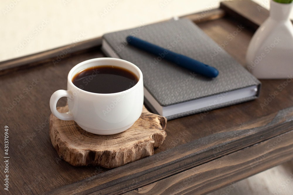 Cup of coffee on a wooden table. Notepad and pen. Breakfast. Office. Workplace. Cup of coffee on a wooden table. Notepad and pen. Breakfast. Office. Workplace.