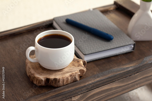 Cup of coffee on a wooden table. Notepad and pen. Breakfast. Office. Workplace.