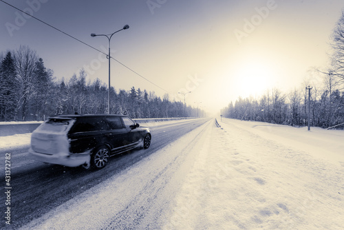 Sunrise on a clear winter morning, the car rides on the highways in the snow. View from the side of the road. Coniferous forest. Russia, Europe. Beautiful nature.