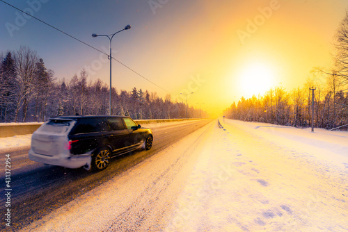 Sunrise on a clear winter morning  the car rides on the highways in the snow. View from the side of the road. Coniferous forest. Russia  Europe. Beautiful nature.