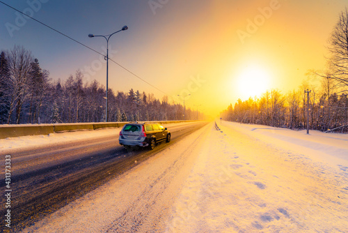 Sunrise on a clear winter morning, the car rides on the highways in the snow. View from the side of the road. Coniferous forest. Russia, Europe. Beautiful nature.
