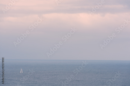 Sailing boat sailing on a vast sea at sunset.