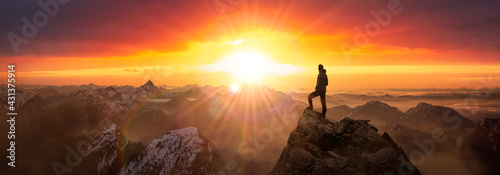 Magical Fantasy Adventure Composite of Man Hiking on top of a rocky mountain peak. Background Landscape from British Columbia, Canada. Sunrise Dramatic Colorful Sky photo