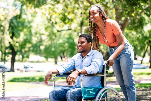 Man in a wheelchair enjoying a walk with his girlfriend.